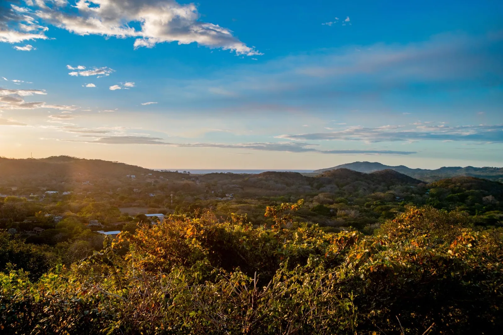 The view from the estate — green hills rolling down to the Pacific under an evening sky